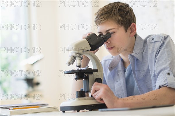 Teenage boy (16-17) looking through microscope.