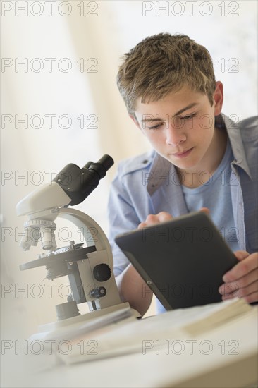 Teenage boy (16-17) using digital tablet in laboratory.