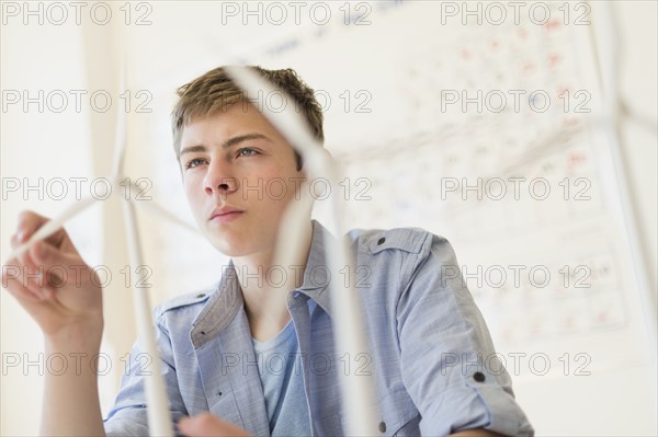 Teenage boy (16-17) touching wind turbines models.