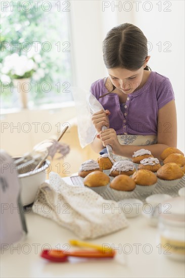girl (10-11) decorating cakes.