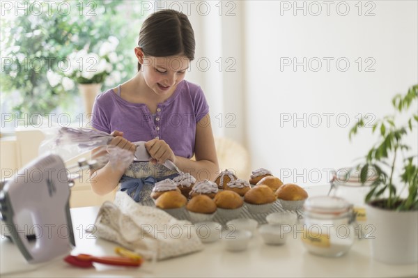 girl (10-11) decorating cakes.