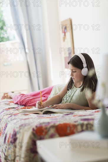 girl (10-11) lying in bed and learning.