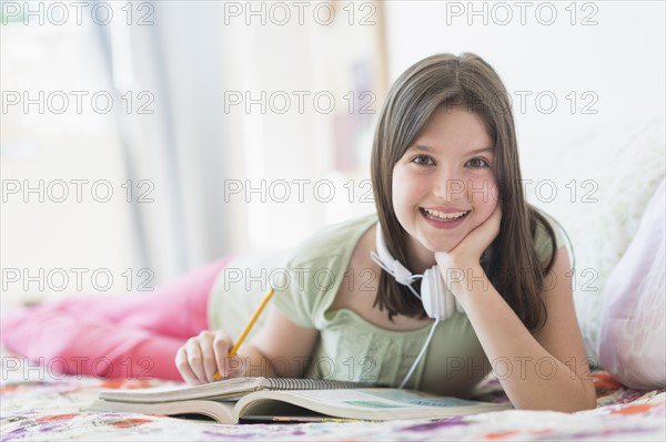 girl (10-11) lying in bed and learning.