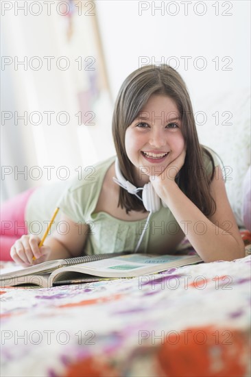 girl (10-11) lying in bed and learning.