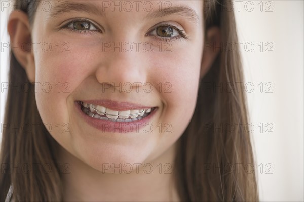 girl (10-11) wearing dental braces smiling.