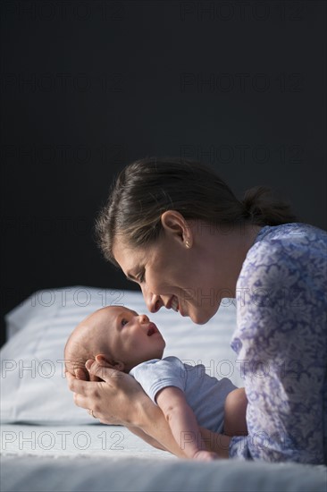 Mother holding baby boy (2-5 months) in bedroom.