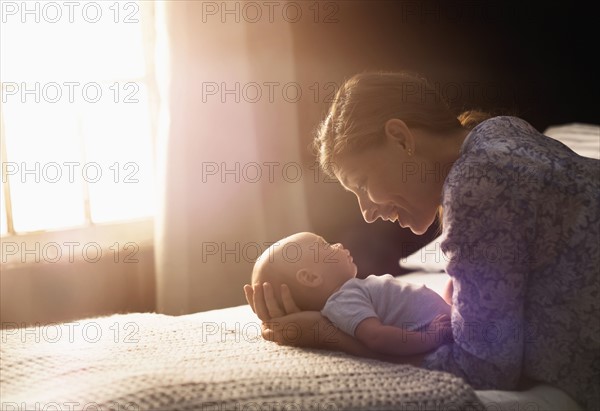 Mother holding baby boy (2-5 months) in bedroom.