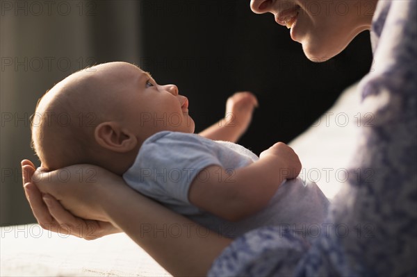 Mother holding baby boy (2-5 months) in bedroom.