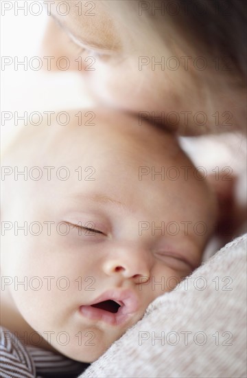 Close up of baby boy (2-5 months) sleeping on mother's shoulder.