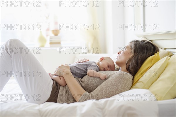 Mother lying in bed with baby boy (2-5 months).