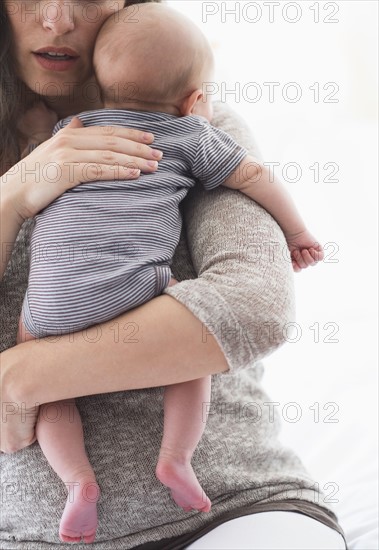 Mother holding baby boy (2-5 months) on her arm.