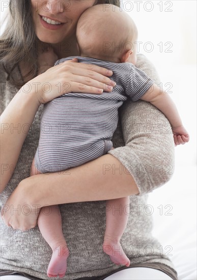 Mother holding baby boy (2-5 months) on her arm.