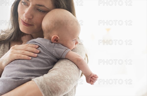 Mother holding baby boy (2-5 months) on her arm.