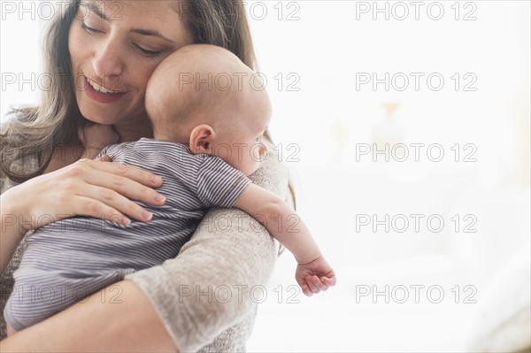 Mother holding baby boy (2-5 months) on her arm.