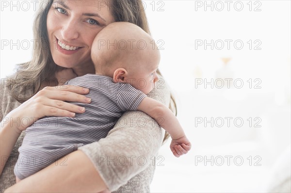 Portrait of smiling mother holding baby boy (2-5 months) on her arm.