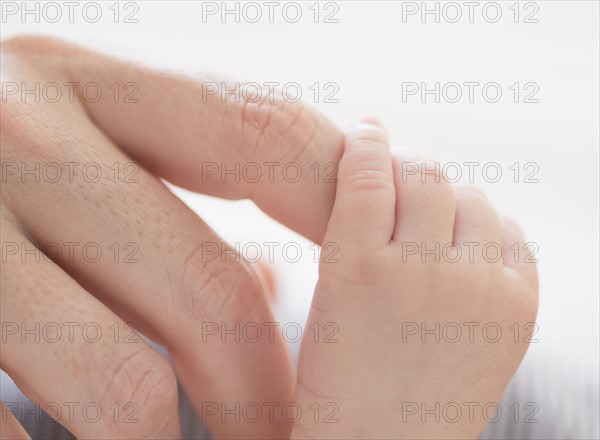 Close up of mother's hand touching baby boy's(2-5 months) foot.