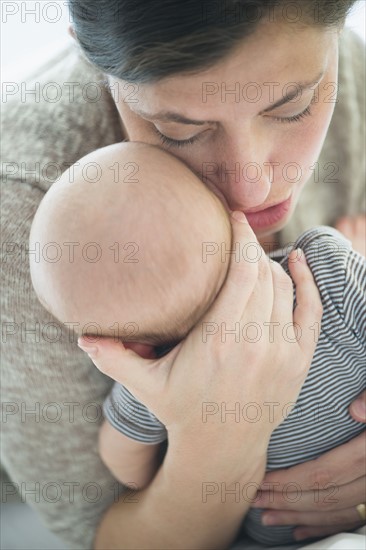 Close up of mother whispering into baby boy's(2-5 months) ear.