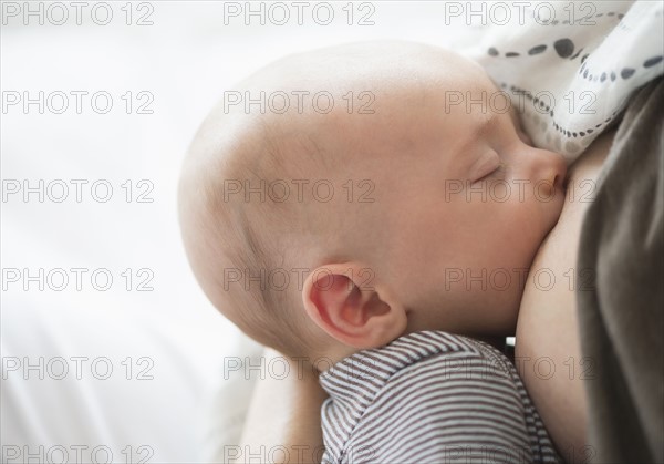 Close up of baby boy (2-5 months) suckling mother's breast.