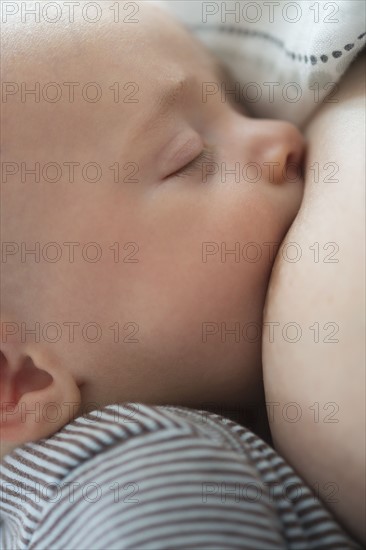 Close up of baby boy (2-5 months) suckling mother's breast.