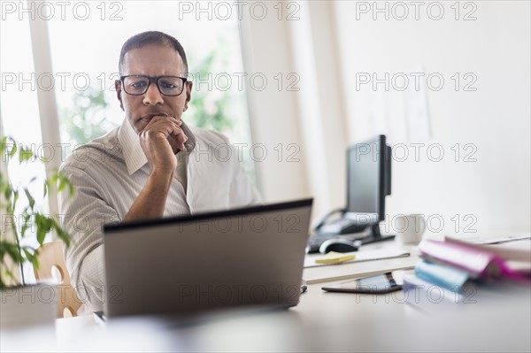 Mature man working with laptop in home office.