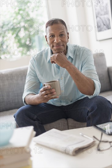 Portrait of man sitting on sofa at home.