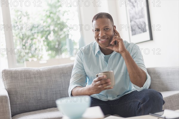 Portrait of man sitting on sofa at home.