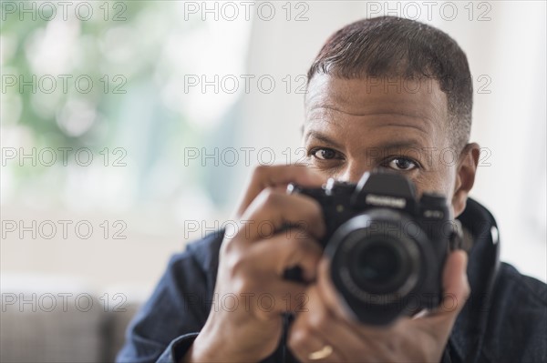 Portrait of man holding digital camera.