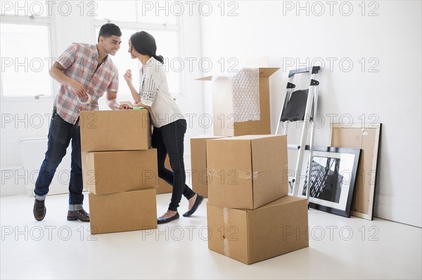 Young couple standing among boxes in new home.