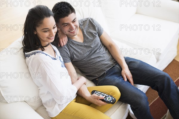 Young couple watching tv on sofa.