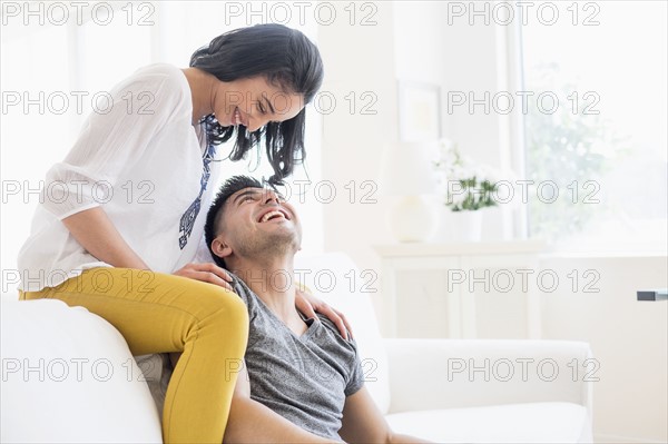 Happy young couple playing on sofa.