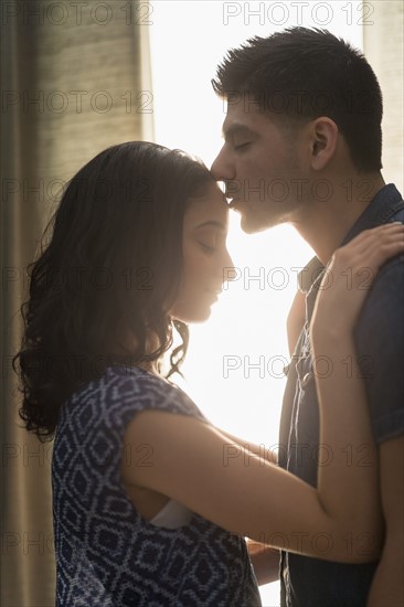 Young couple kissing in sunlight.