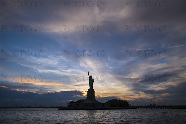 Silhouette of Statue of Liberty at sunset.