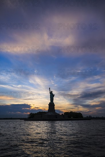 Silhouette of Statue of Liberty at sunset.