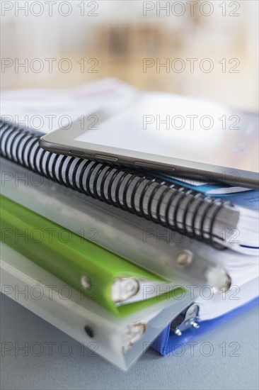 Close up of stack of notebooks with digital tablet on top.