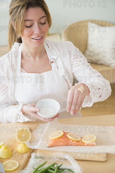 Young woman seasoning salmon.
Photo : Jamie Grill