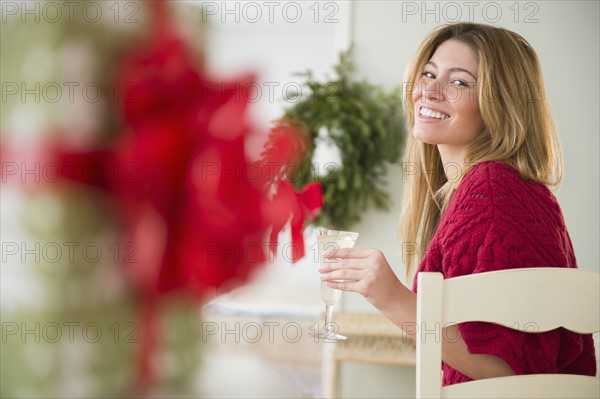 Young woman holding champagne flute at christmas.
Photo : Jamie Grill