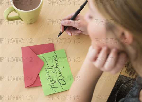 Woman writing greeting card at christmas.
Photo : Jamie Grill