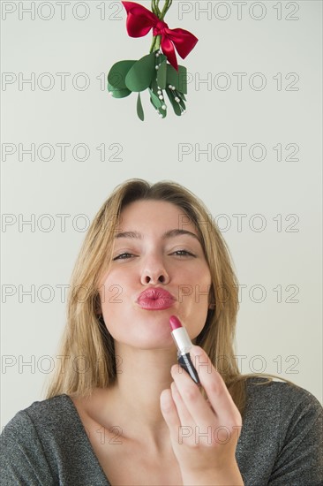 Young woman puckering under mistletoe.
Photo : Jamie Grill