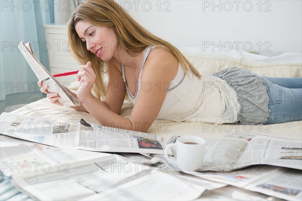 Young woman lying on bed and doing job search.
Photo : Jamie Grill