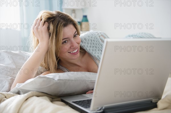 Young woman lying in bed and using laptop.
Photo : Jamie Grill