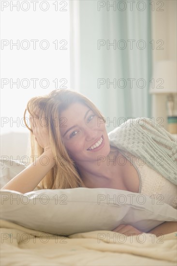 Portrait of young woman lying in bed.
Photo : Jamie Grill