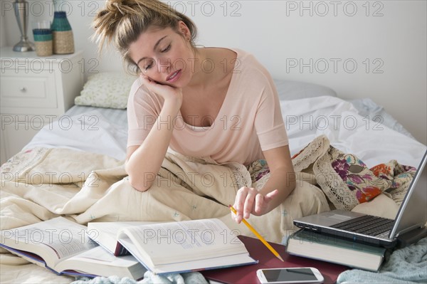 Young woman studing in bed.
Photo : Jamie Grill