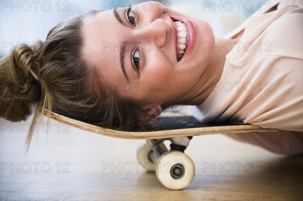 Portrait of young woman lying down on skateboard.
Photo : Jamie Grill