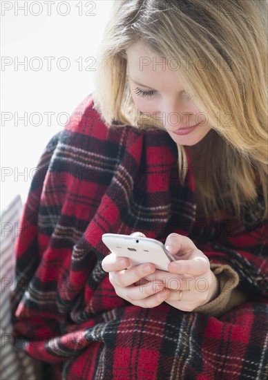 Woman wrapped in blanket text messaging.
Photo : Jamie Grill