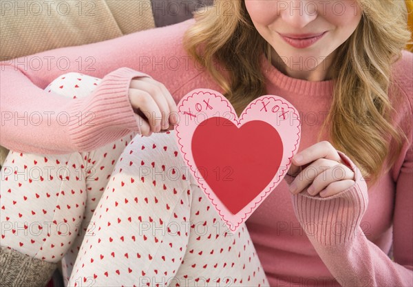 Woman holding heart shape valentine's card.
Photo : Jamie Grill