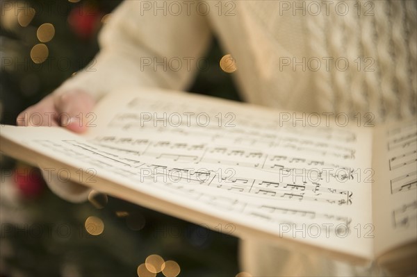 Studio Shot of woman holding sheet music at christmas.
Photo : Jamie Grill