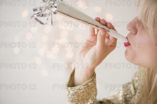 Studio Shot of woman blowing noicemaker at party.
Photo : Jamie Grill