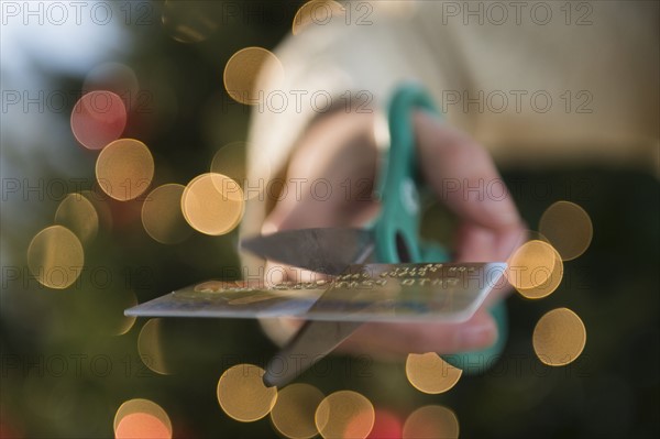 Studio Shot of female hand cutting credit card with scissors.
Photo : Jamie Grill