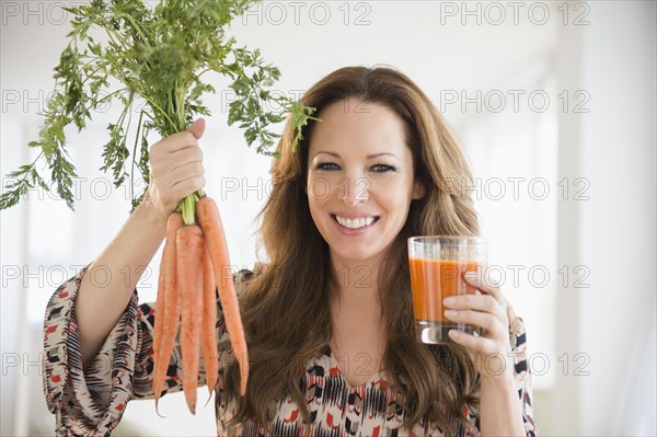 Portrait of woman holding carrots and carrot juice.
Photo : Jamie Grill