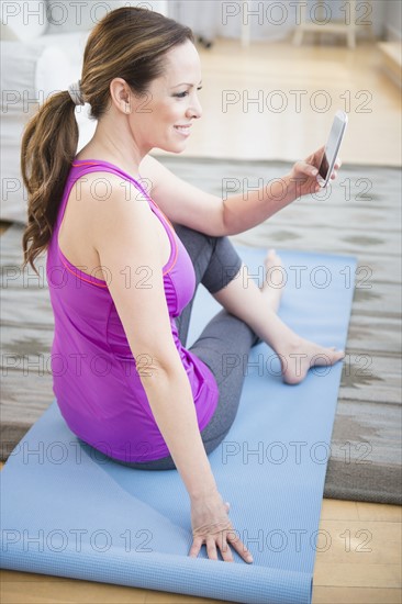 Woman exercising and holding mobile phone .
Photo : Jamie Grill